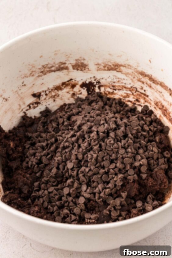 Mini chocolate chips being added to chocolate cookie dough.