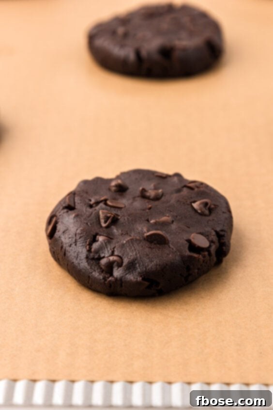 Chocolate cookies on parchment baking sheet ready to bake.