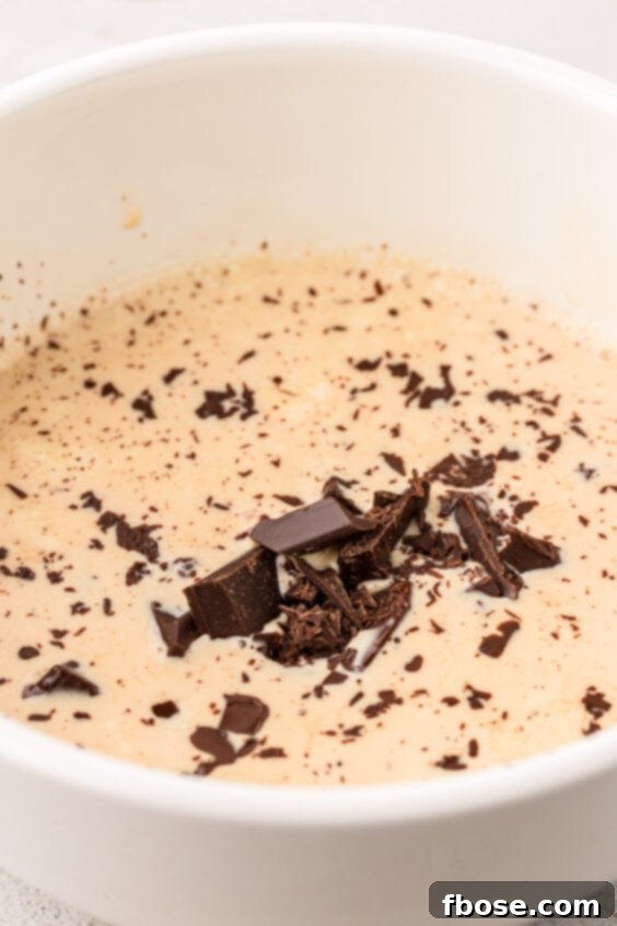 Chopped chocolate and hot cream in a bowl to make ganache.