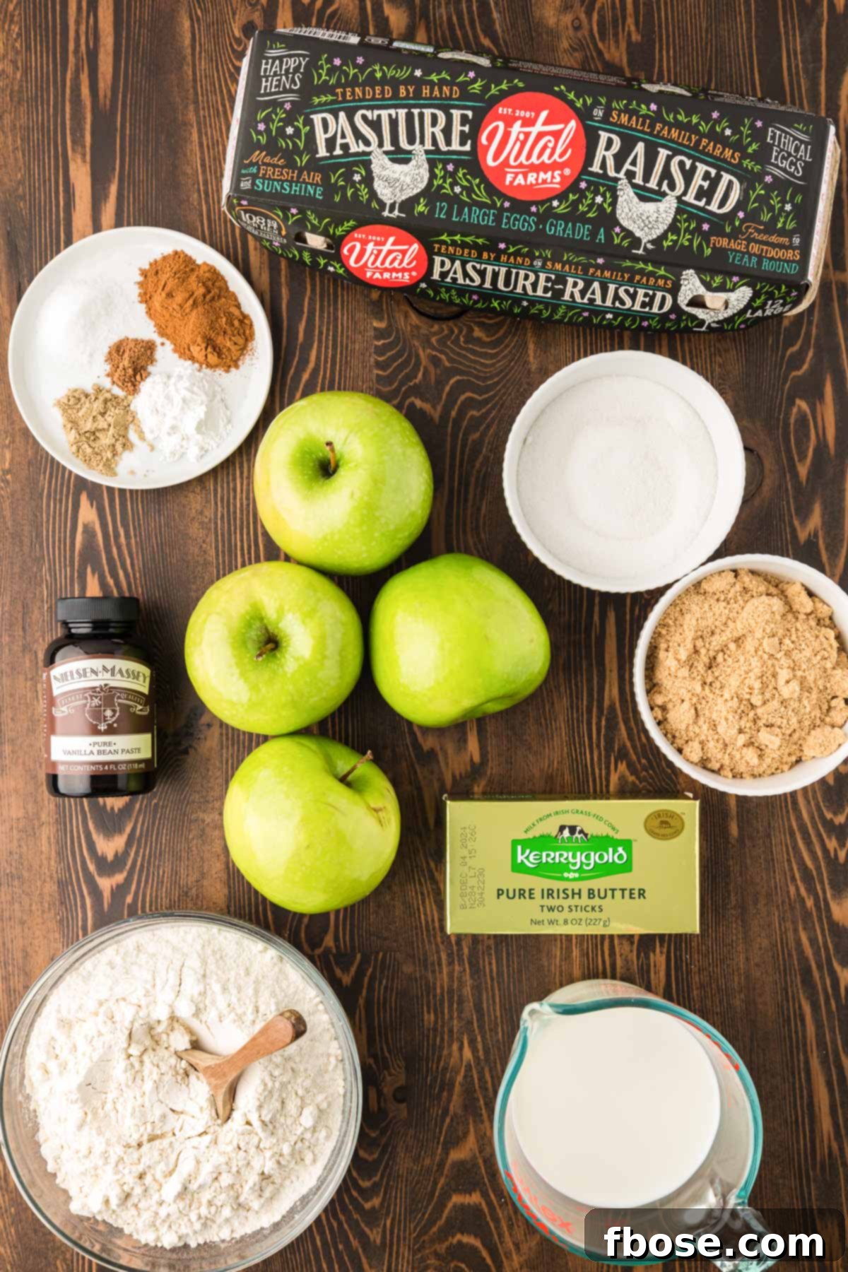 A beautiful flat lay photograph showcasing all the fresh ingredients needed to make Irish Apple Cake arranged aesthetically on a rustic wooden table.