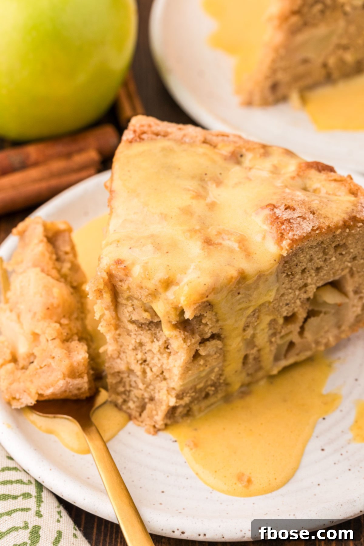 A delightful slice of Irish Apple Cake resting on a pristine white plate, with a fork holding a perfect bite, showcasing the moist texture and chunky apples.