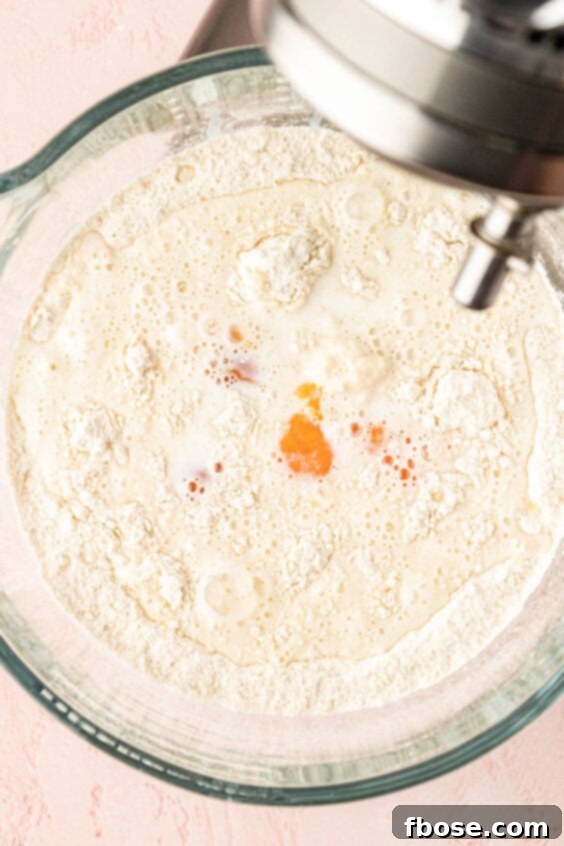 Milk and eggs being added to dry ingredients to make cinnamon roll dough.