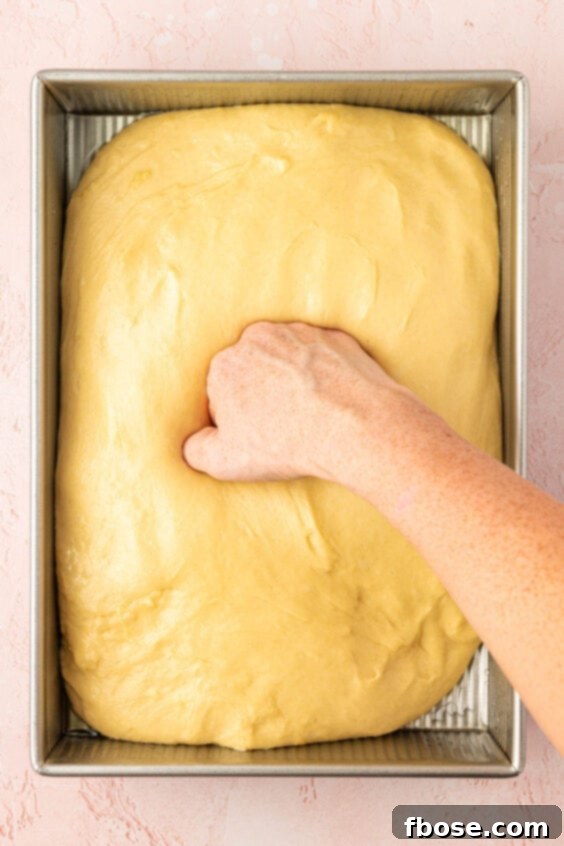 Dough being punched dough in a 9x13-inch baking pan.
