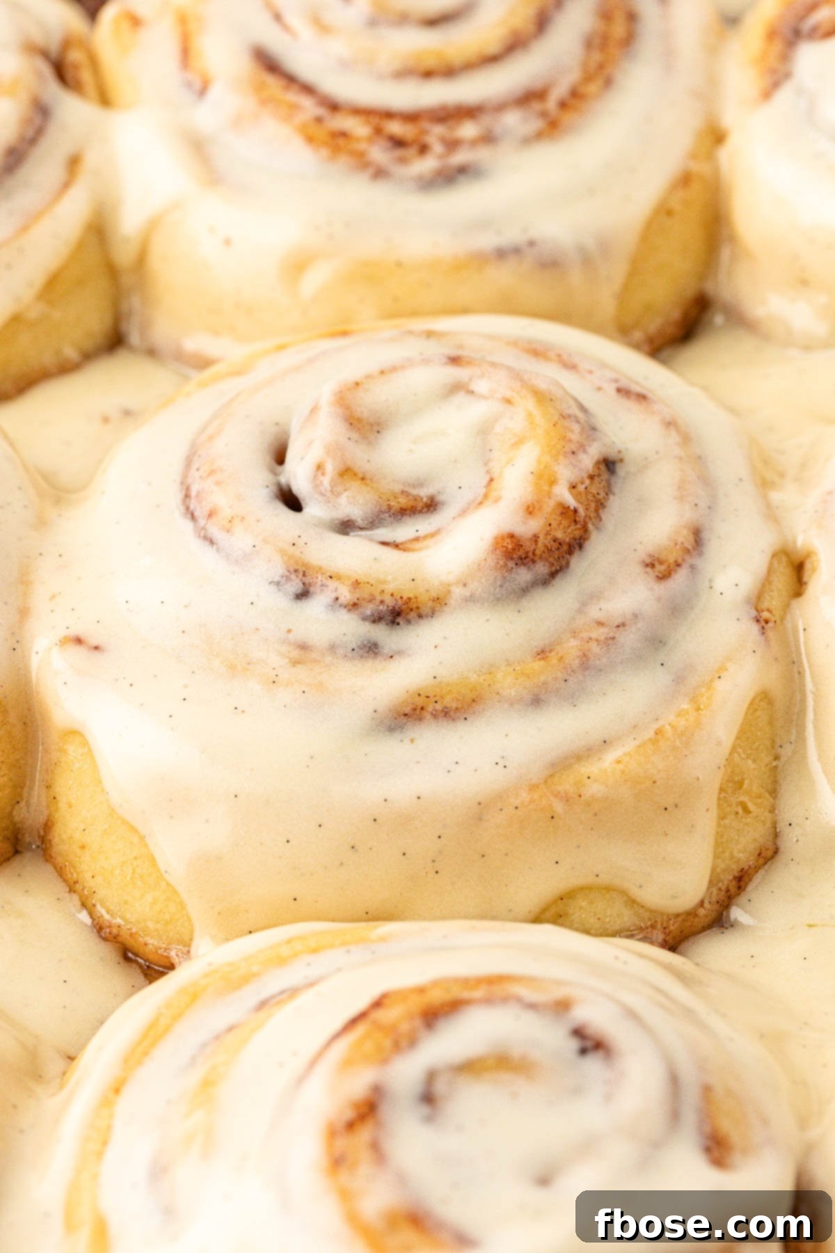 Close up of iced cinnamon rolls on a pan.