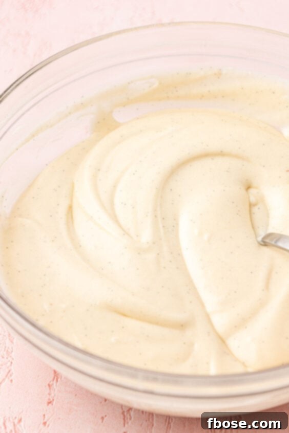 Cream cheese icing in a glass mixing bowl.
