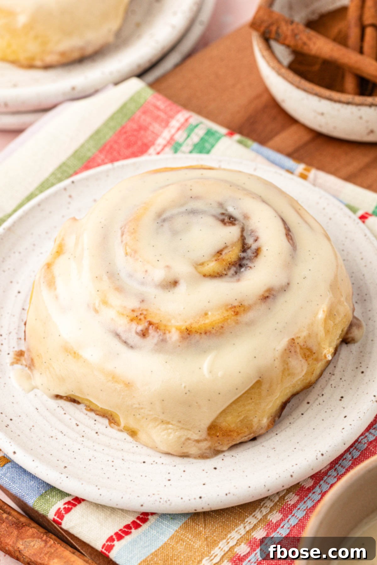 Close up photo of a large cinnamon roll on a white plate.