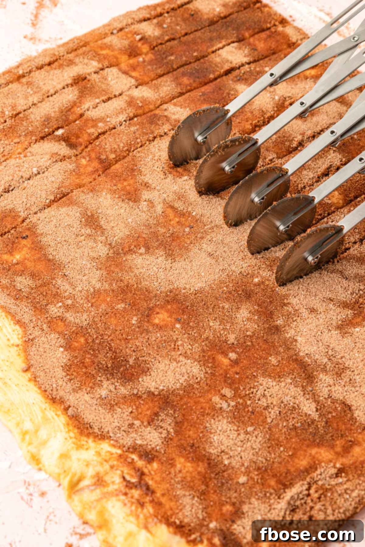 A pastry cutter rolling through cinnamon roll dough.
