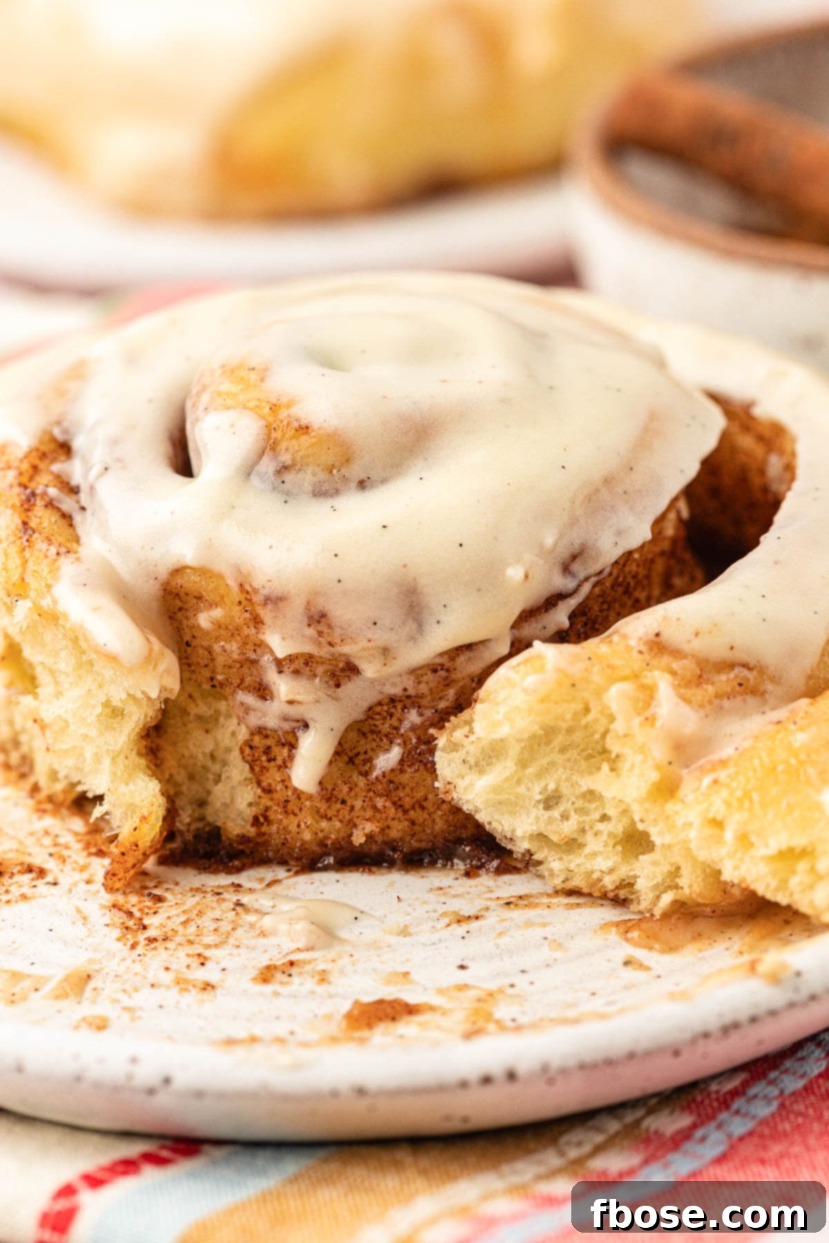 Close up of Amish potato cinnamon rolls on a plate with a bite missing.