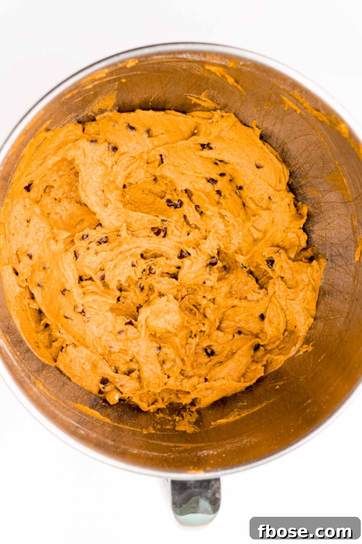 Overhead photo of mixing bowl filled with pumpkin chocolate chip cookie dough.