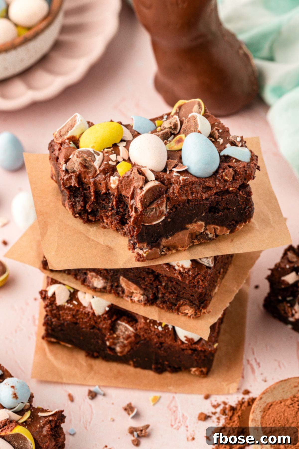 Molten Cadbury Egg Brownies 9 A beautifully arranged stack of three Cadbury Egg Brownies on a rustic wooden table.