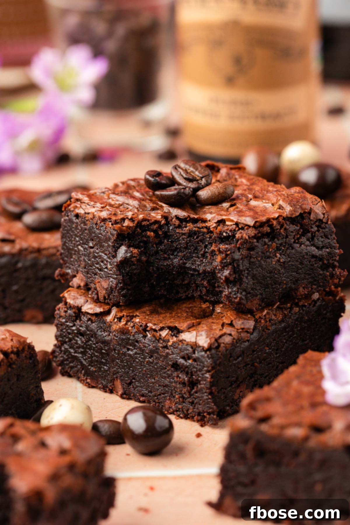 Coffee Brownies 7 Close up of two brownies stacked with the top one missing a bite and espresso beans scattered around.