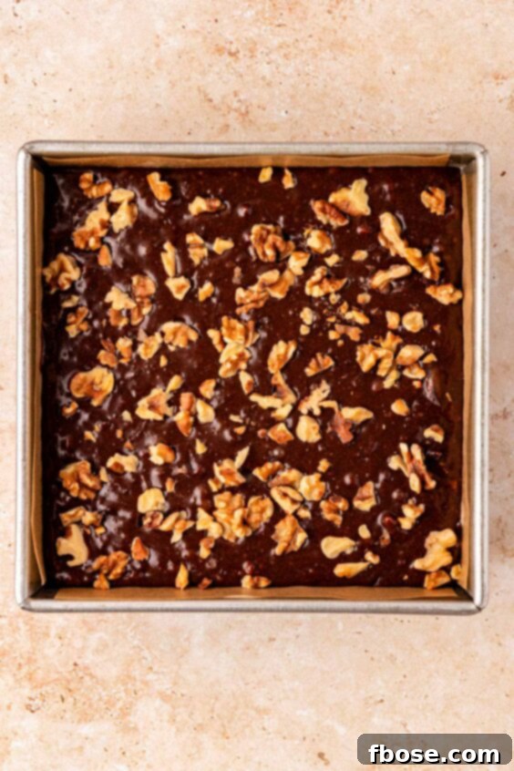 Brownie batter in a pan topped with walnuts.