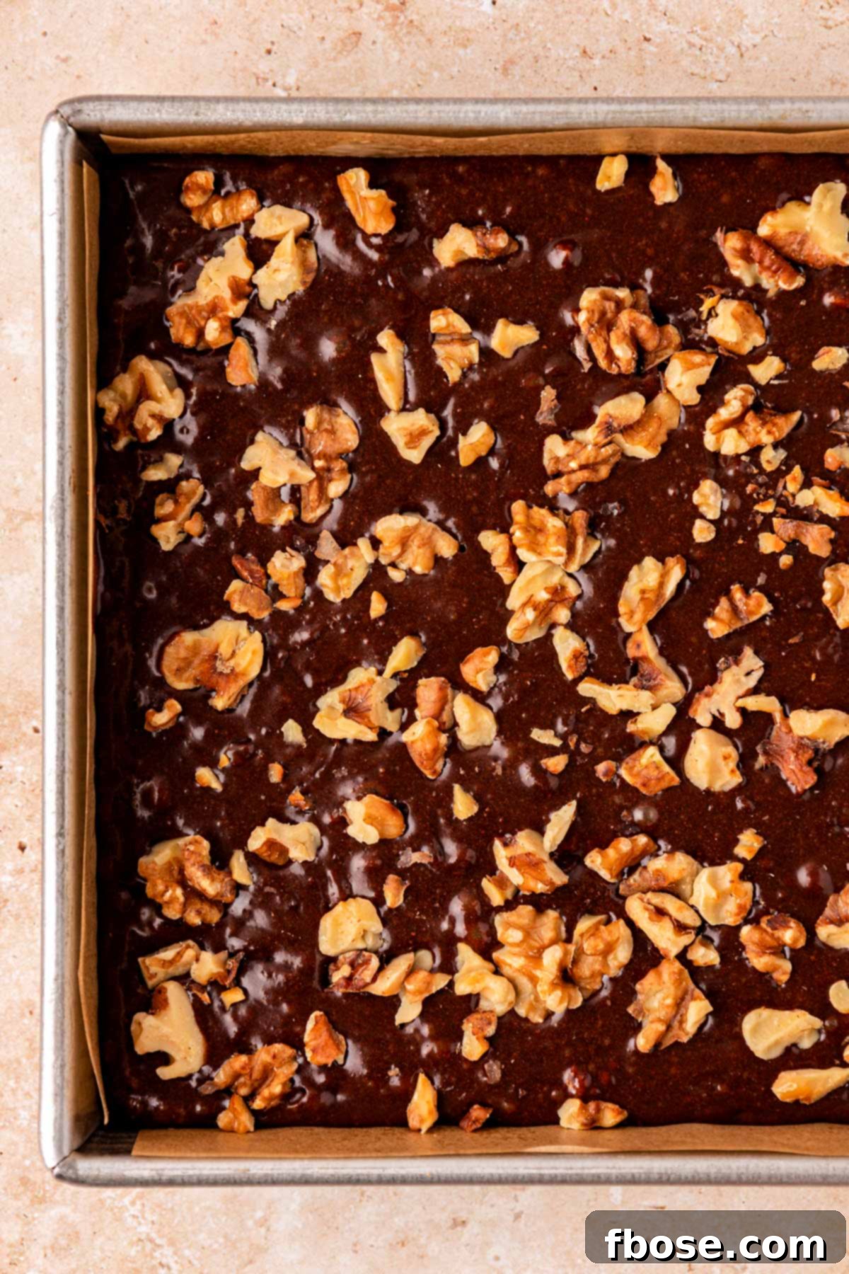 Close up of brownie batter in a pan topped with walnuts.