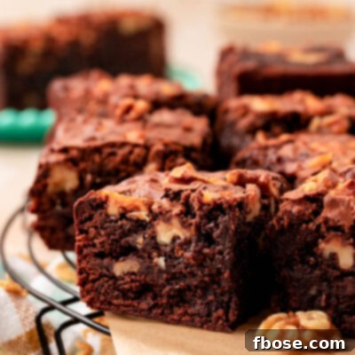 Close up of a brownie with walnuts on a piece of parchment paper.
