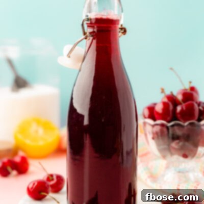A bottle of cherry simple syrup on a table.