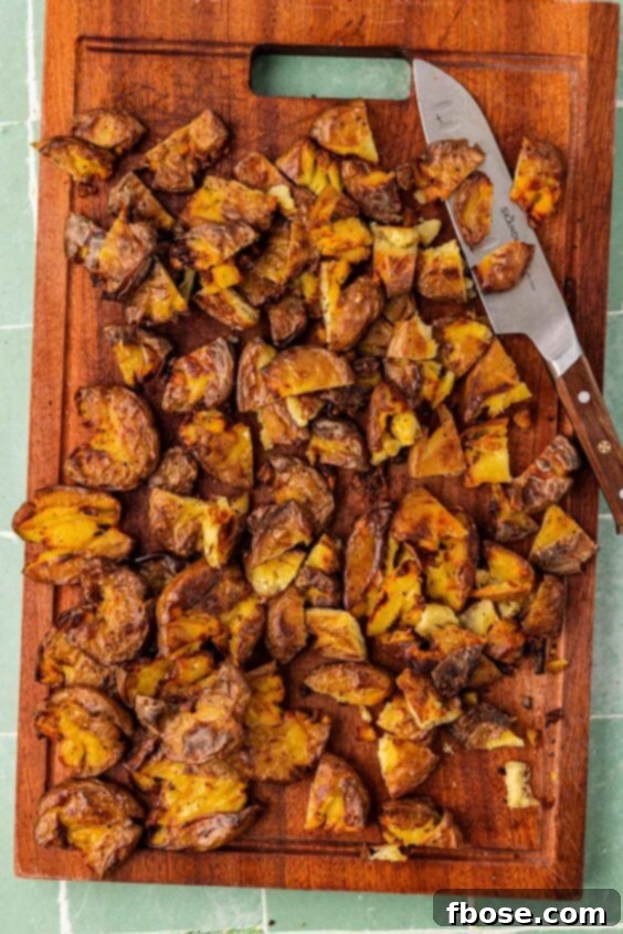 Chopped smashed potatoes on a cutting board.
