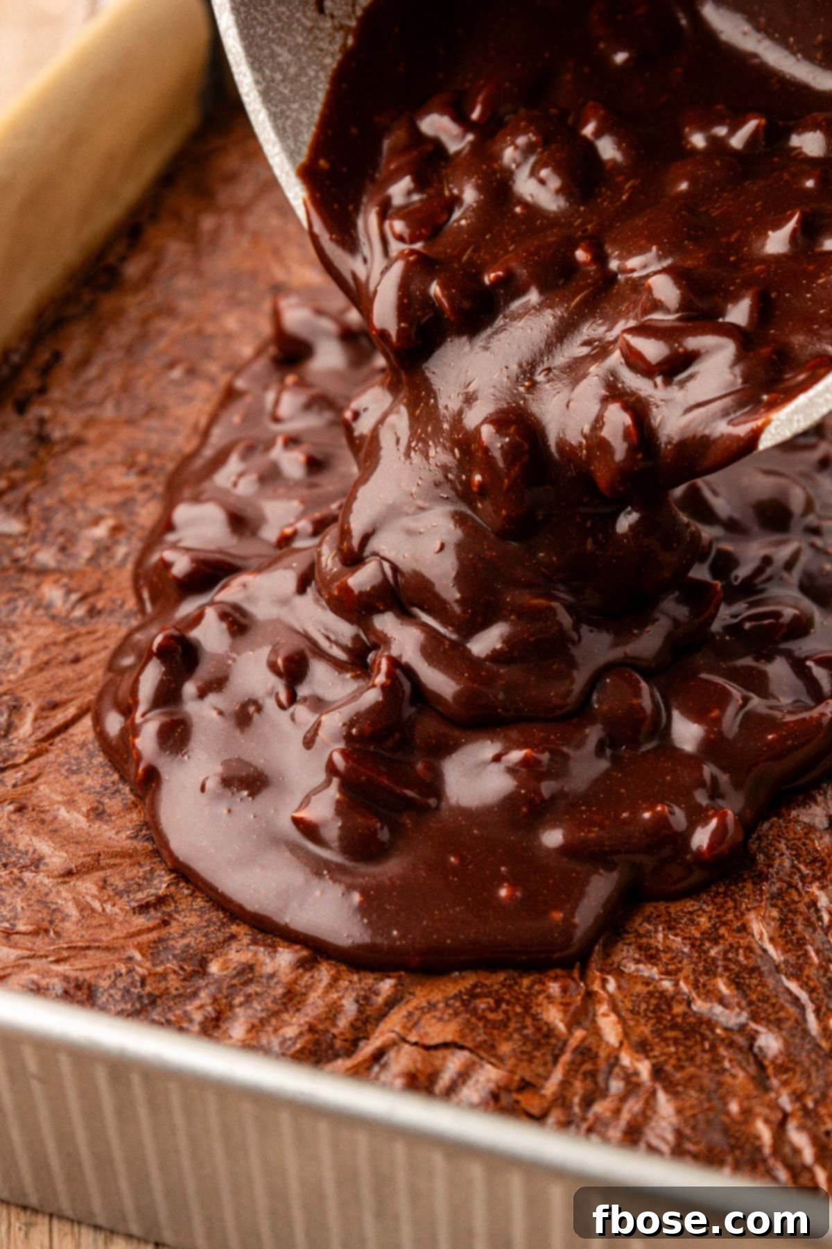 Texas Sheet Cake Icing being poured on brownies in a pan, capturing the luscious moment.