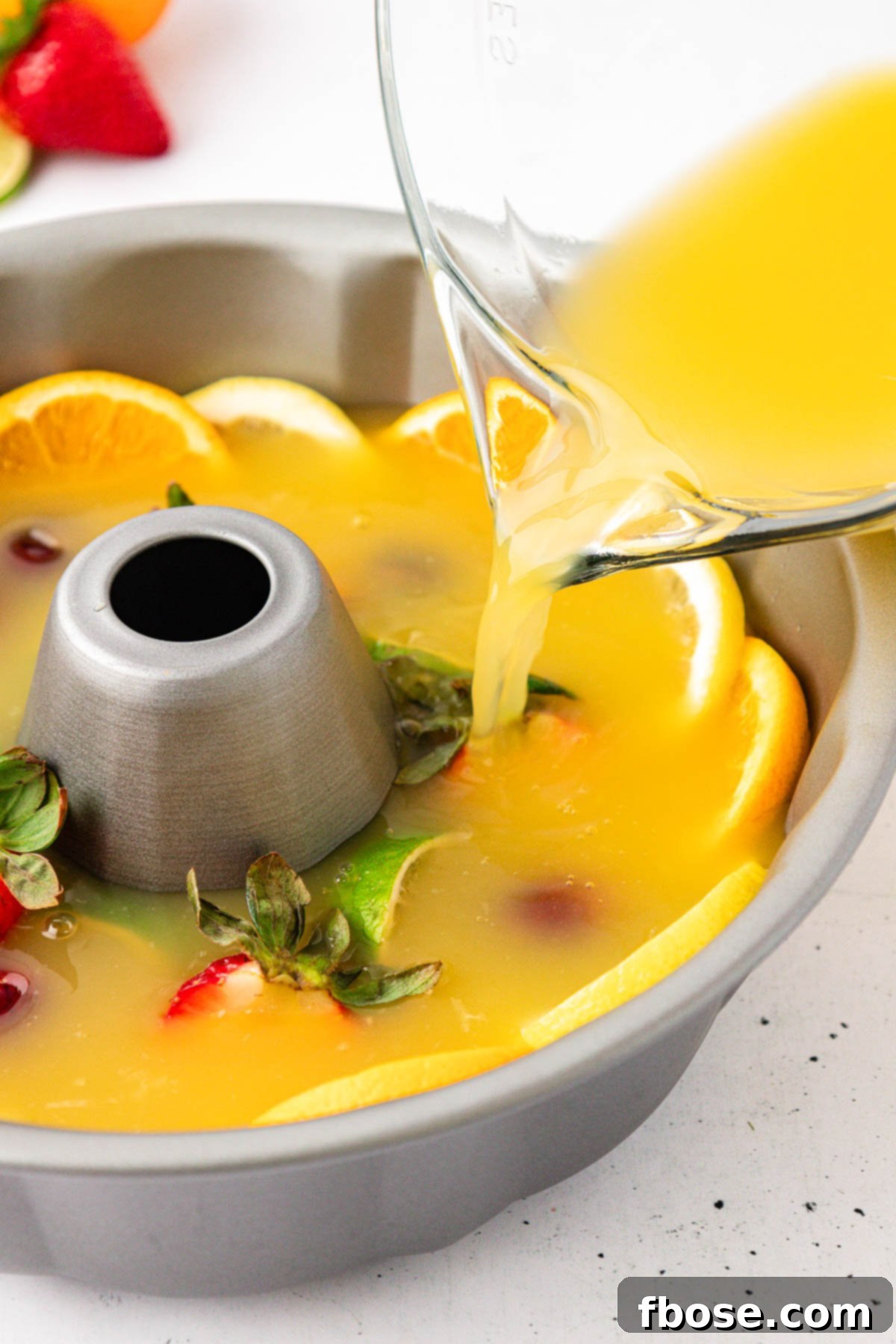 Punch being poured into a bundt pan with fruit.