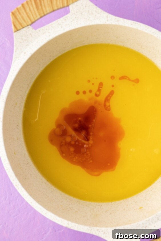 Vanilla extract and canola oil added to a melted butter and sugar mixture in a pot.