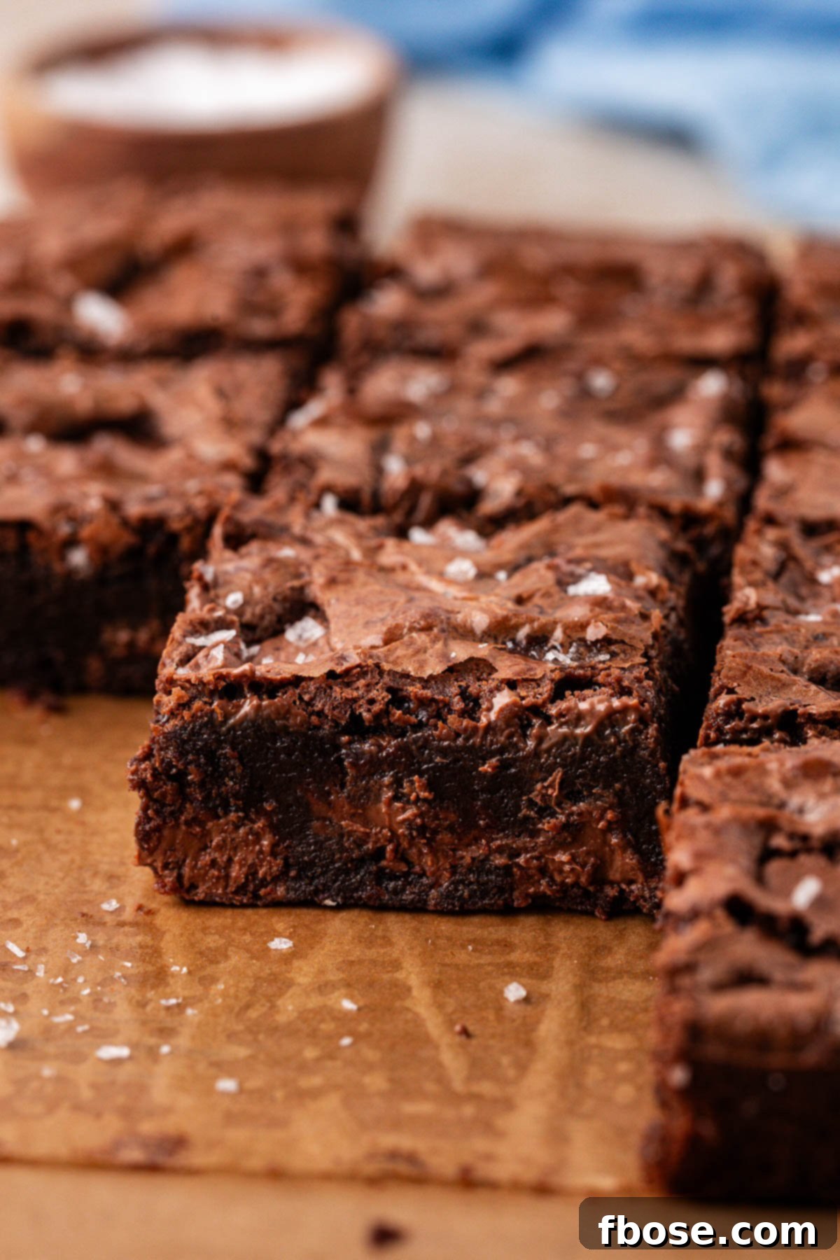 Close up of chocolate chunk brownies on a piece of parchment paper.