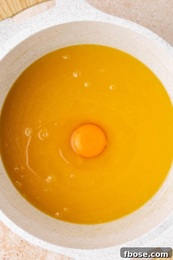 An egg in a pot with melted butter and sugar.