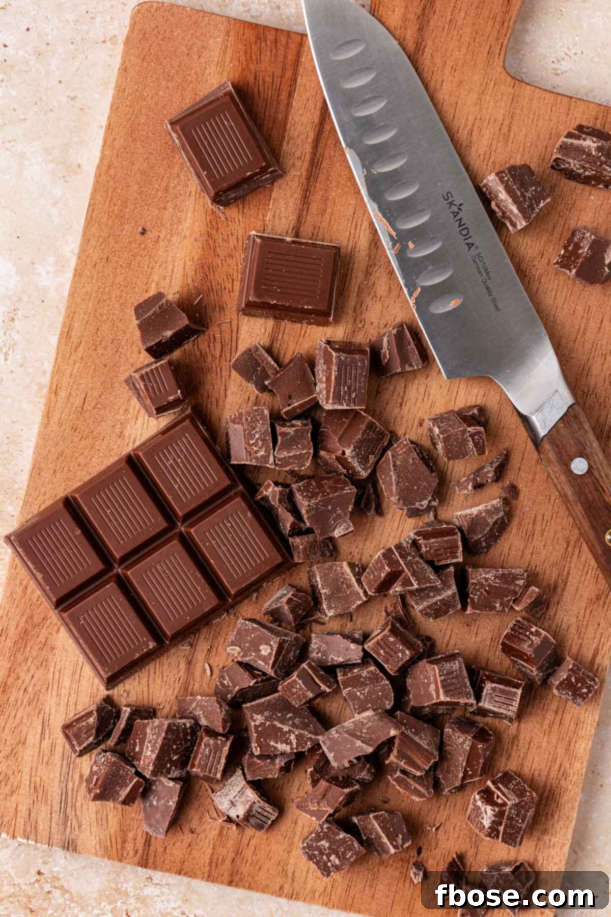 Chopped chocolate on a cutting board with a knife.