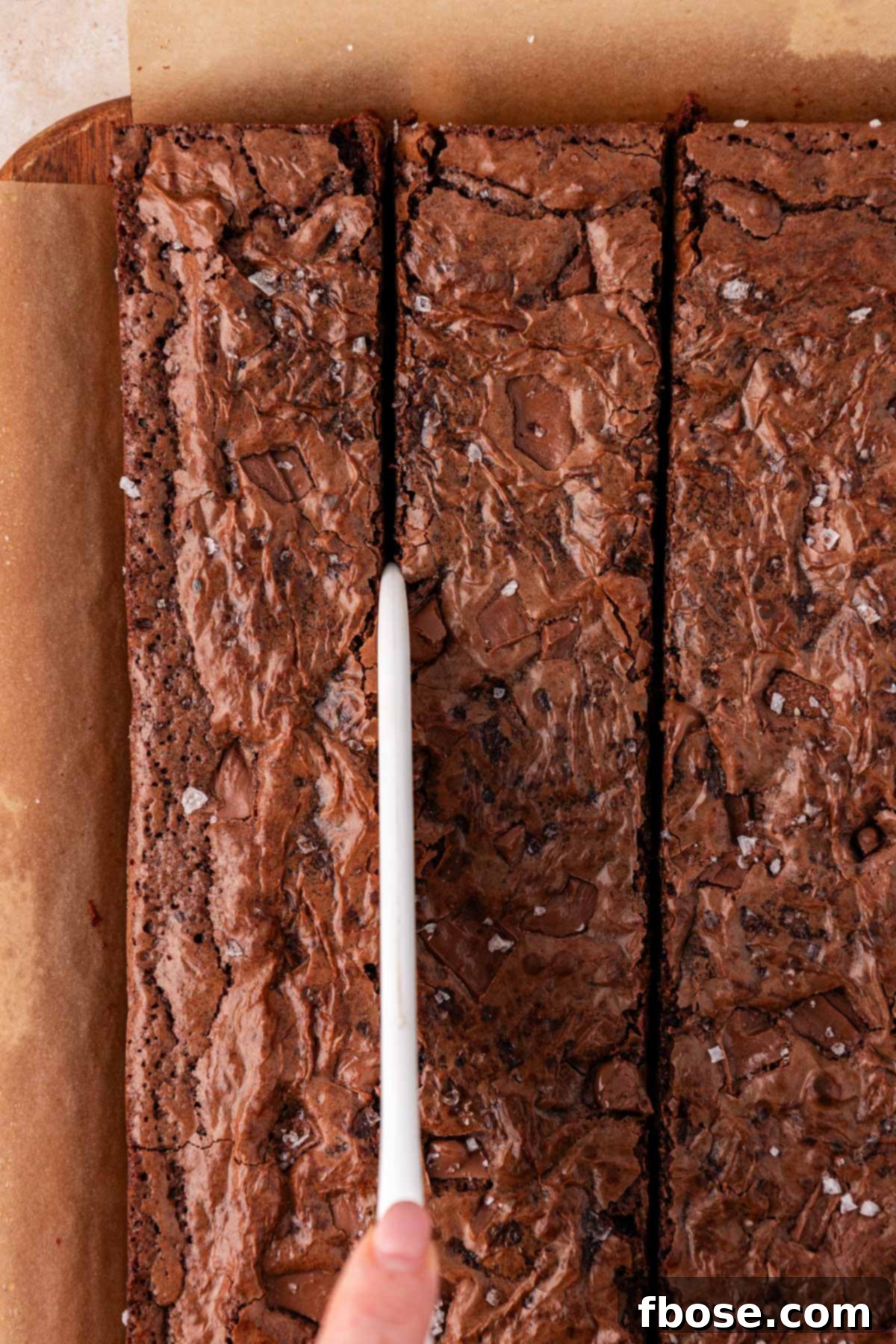 Overhead shot of brownies being cut with a large plastic knife.