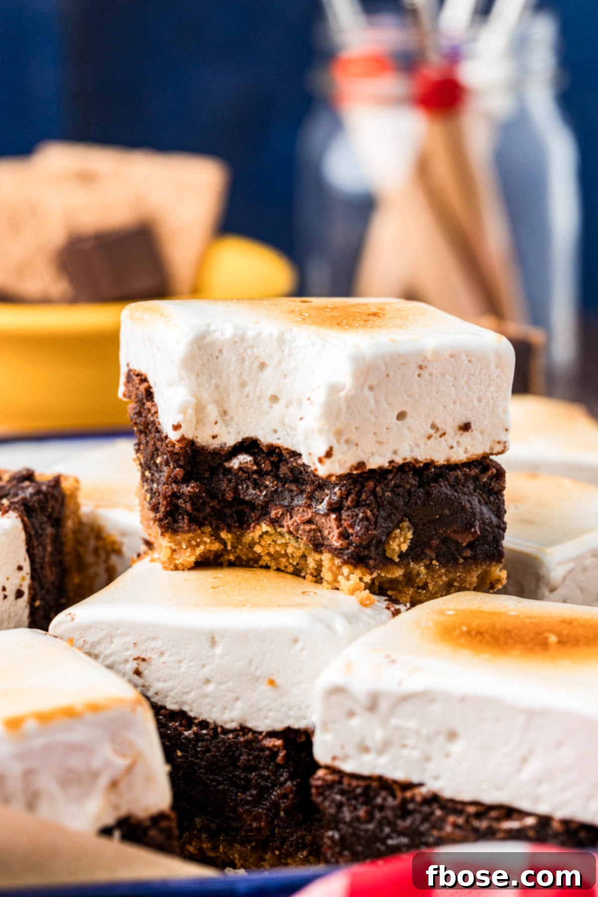 S'mores Brownies on a table, one stacked on top of another with a bite missing from it.