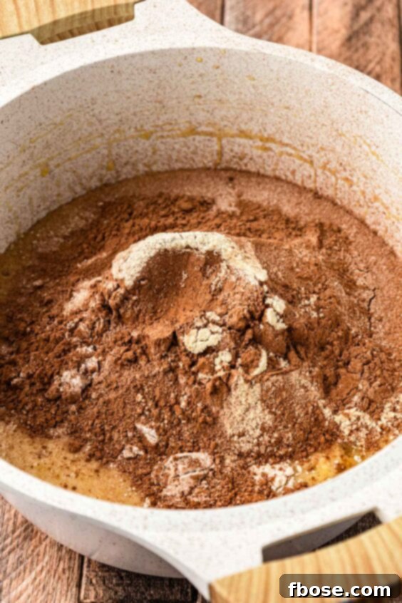 Cocoa powder and flour sifted into a pot to make brownie batter.