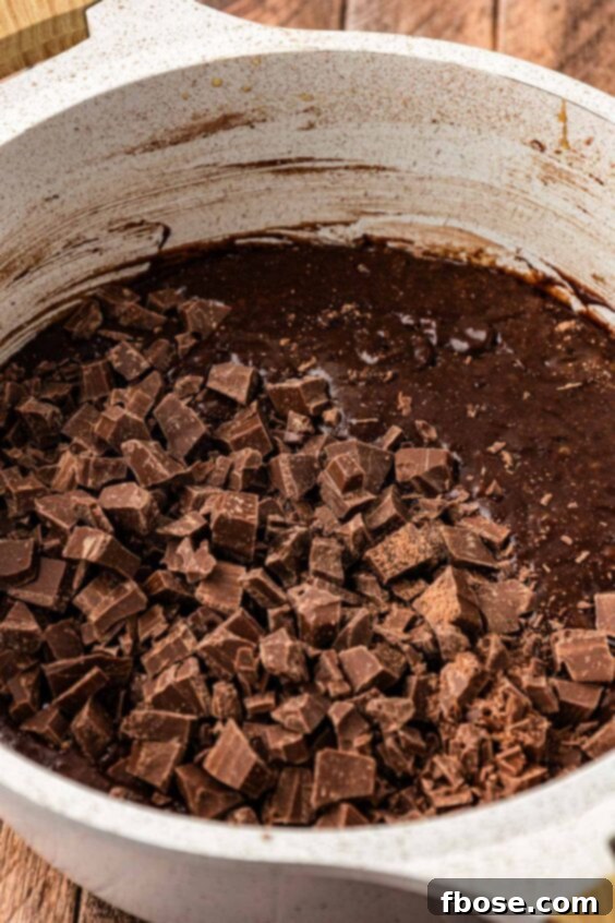 chopped chocolate being added to a pot with brownie batter.