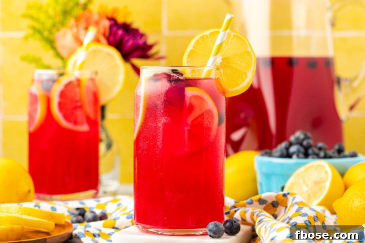 Several glasses of blueberry lemonade, adorned with fresh blueberries and lemon slices, presented on a rustic wooden table.