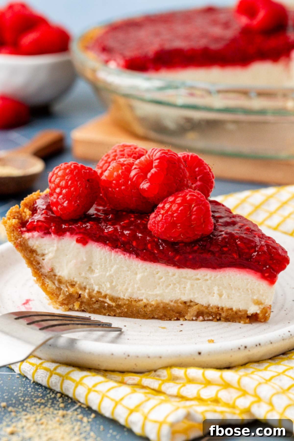 A beautiful slice of No Bake Raspberry Cream Pie on a white plate, showcasing its creamy layers and vibrant raspberry topping.