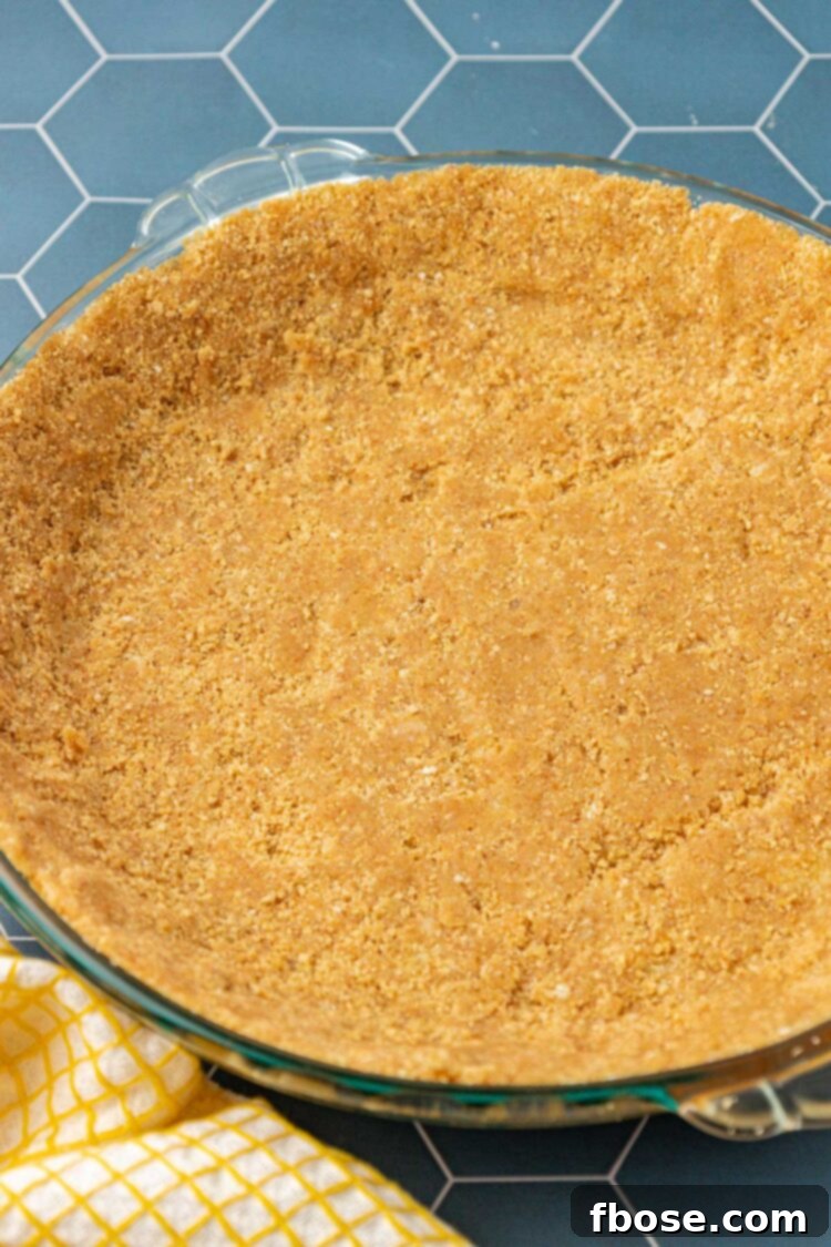 A perfectly formed graham cracker pie crust resting on a blue table, ready for filling.