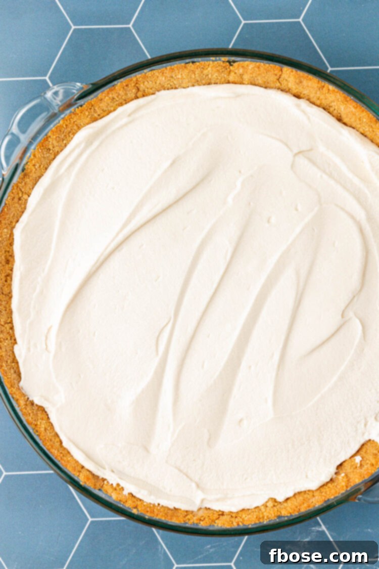 Creamy pie filling meticulously spread into a pie dish, forming an even layer.