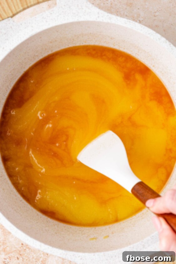 Vanilla being stirred into butter and sugar in a saucepan.