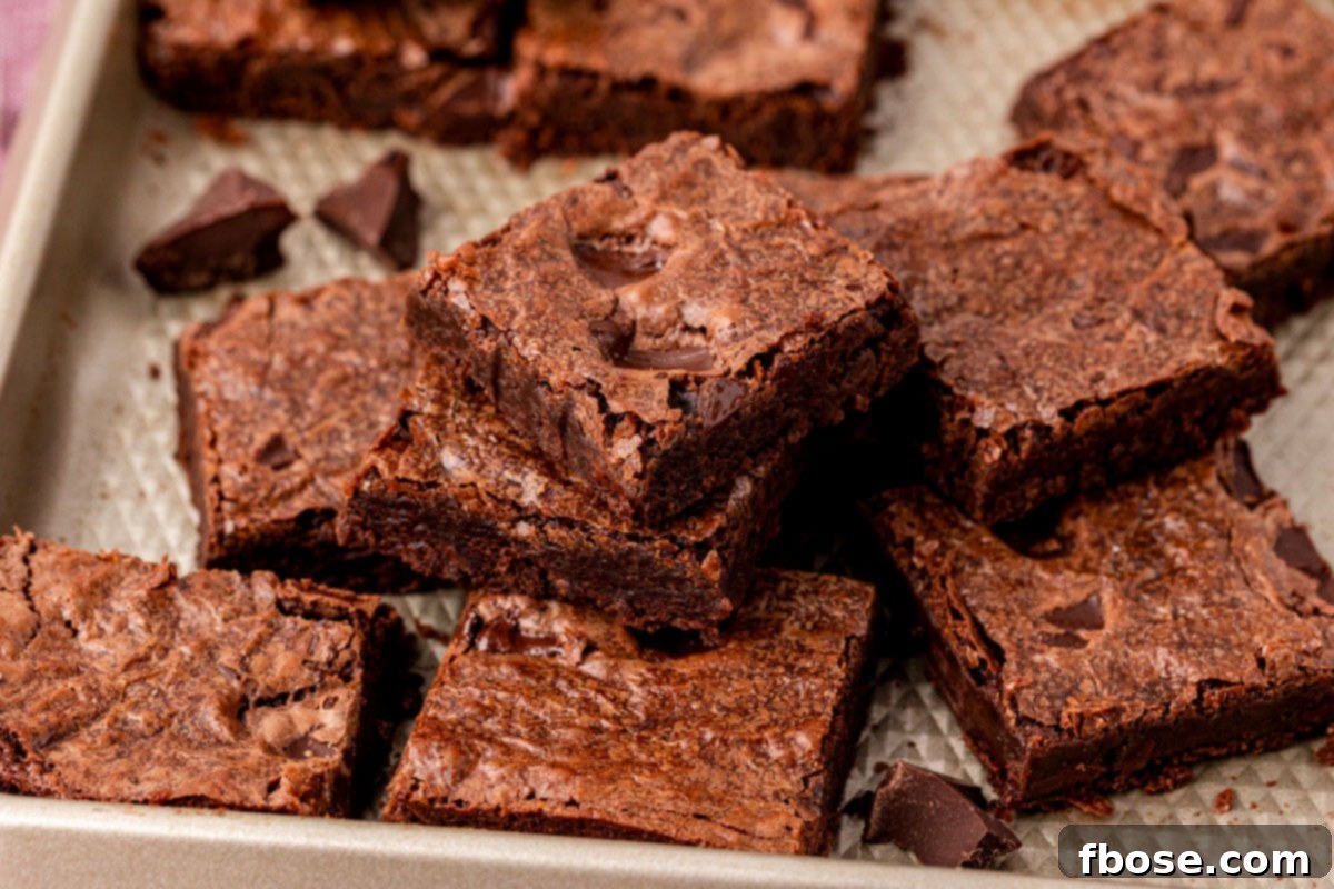 Sheet pan brownies cut up and stacked on a sheet pan.
