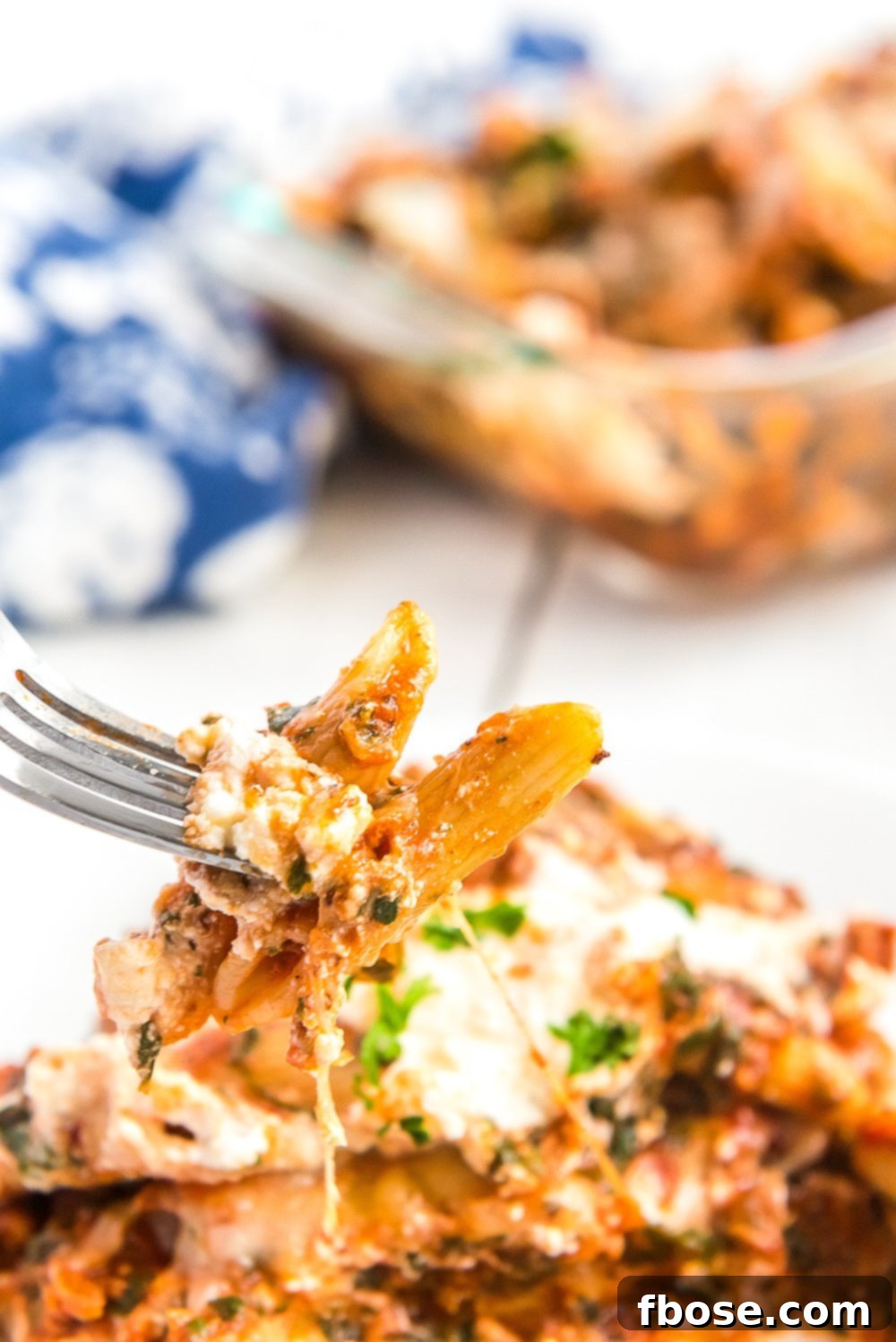 A fork holding a bite of penne pasta from a delicious Turkey Florentine pasta bake.