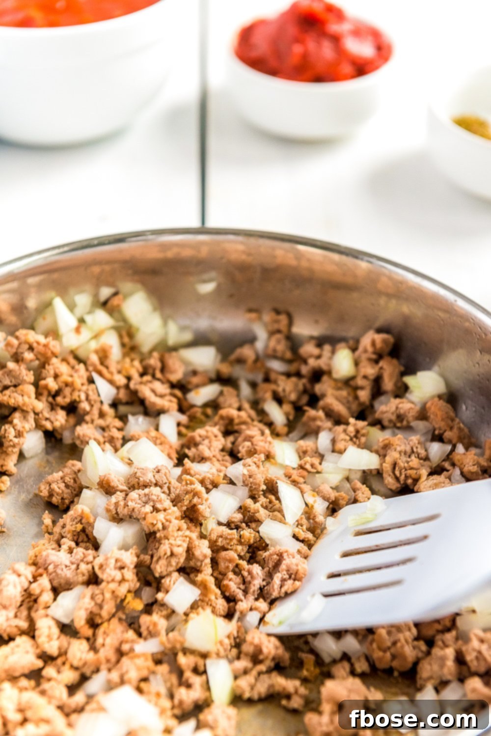 Ground turkey and diced sweet onions browning in a large non-stick skillet.