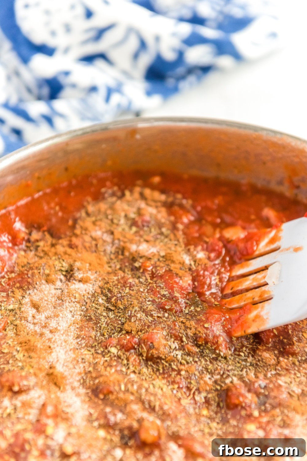 Rich red marinara sauce, tomato paste, and spices simmering in a skillet with browned turkey and onions.