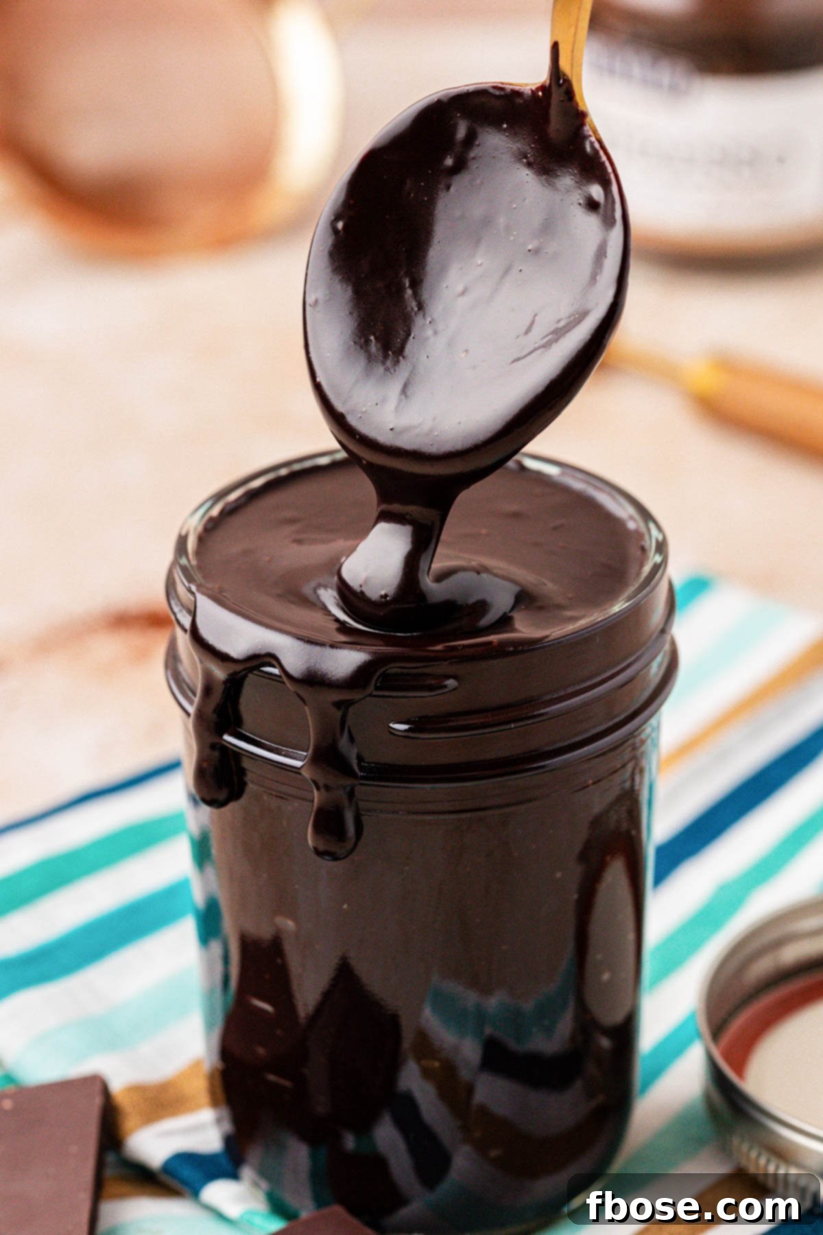 Rich Hot Fudge Sauce 2 Close up of a spoon scooping hot fudge from a jar.