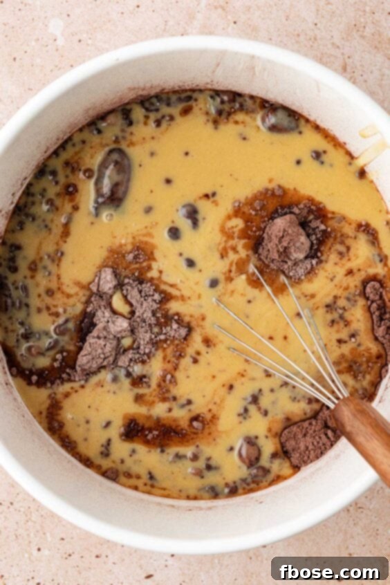 Wet ingredients poured into dry ingredients in a bowl to make chocolate muffins.