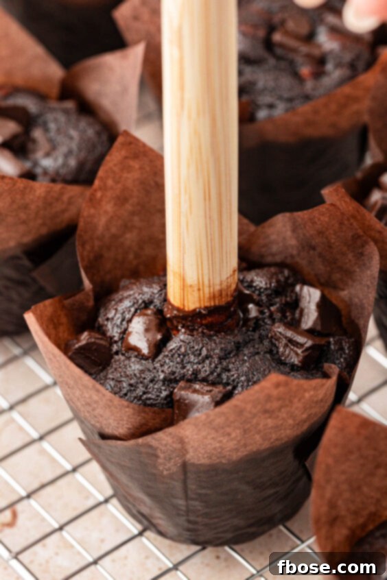 A wooden dowel poking a hole in a chocolate muffin.
