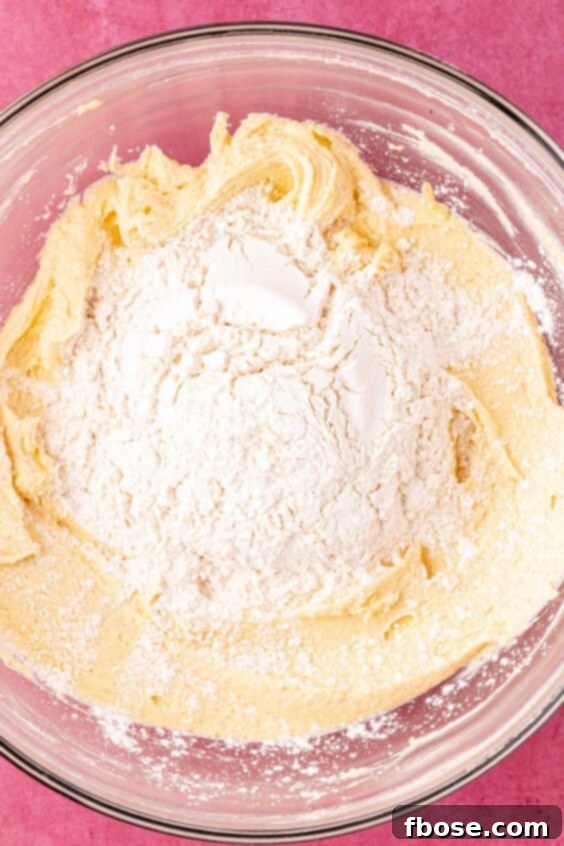 Dry ingredients being added to wet ingredients in a bowl.