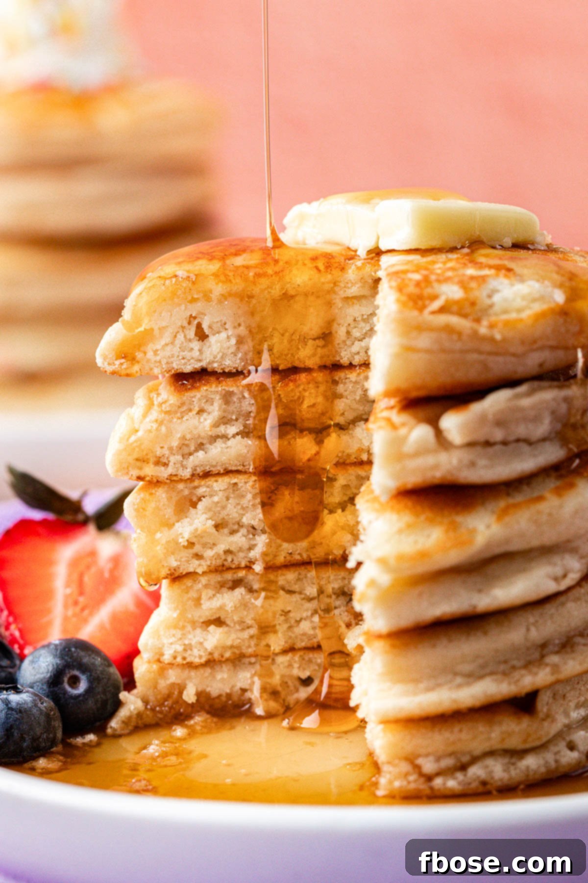 Rich maple syrup being generously poured over a stack of golden brown ice cream pancakes, creating a mouth-watering cascade.