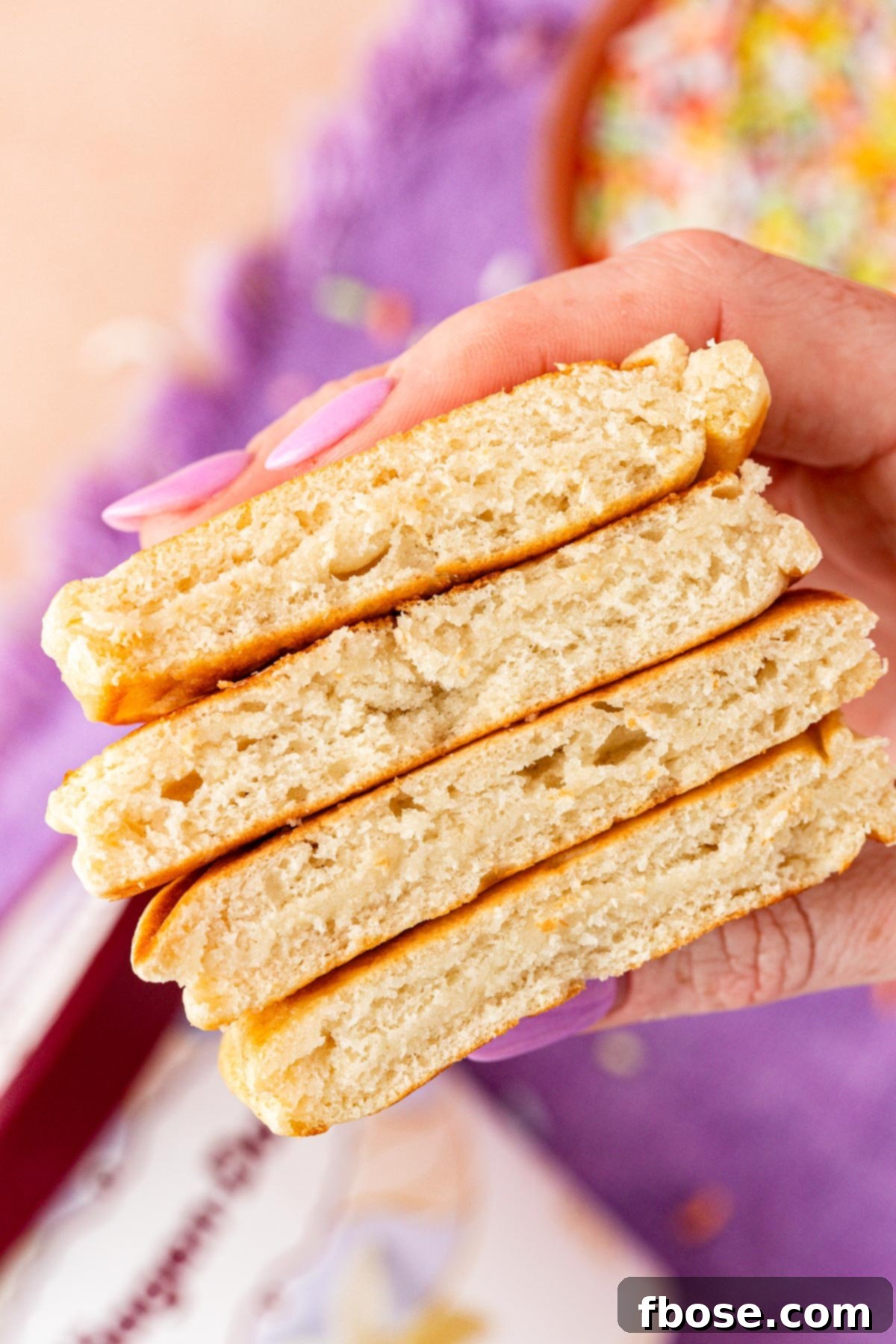 A woman's hand holding a fluffy ice cream pancake cut in half, showcasing its light and airy texture.