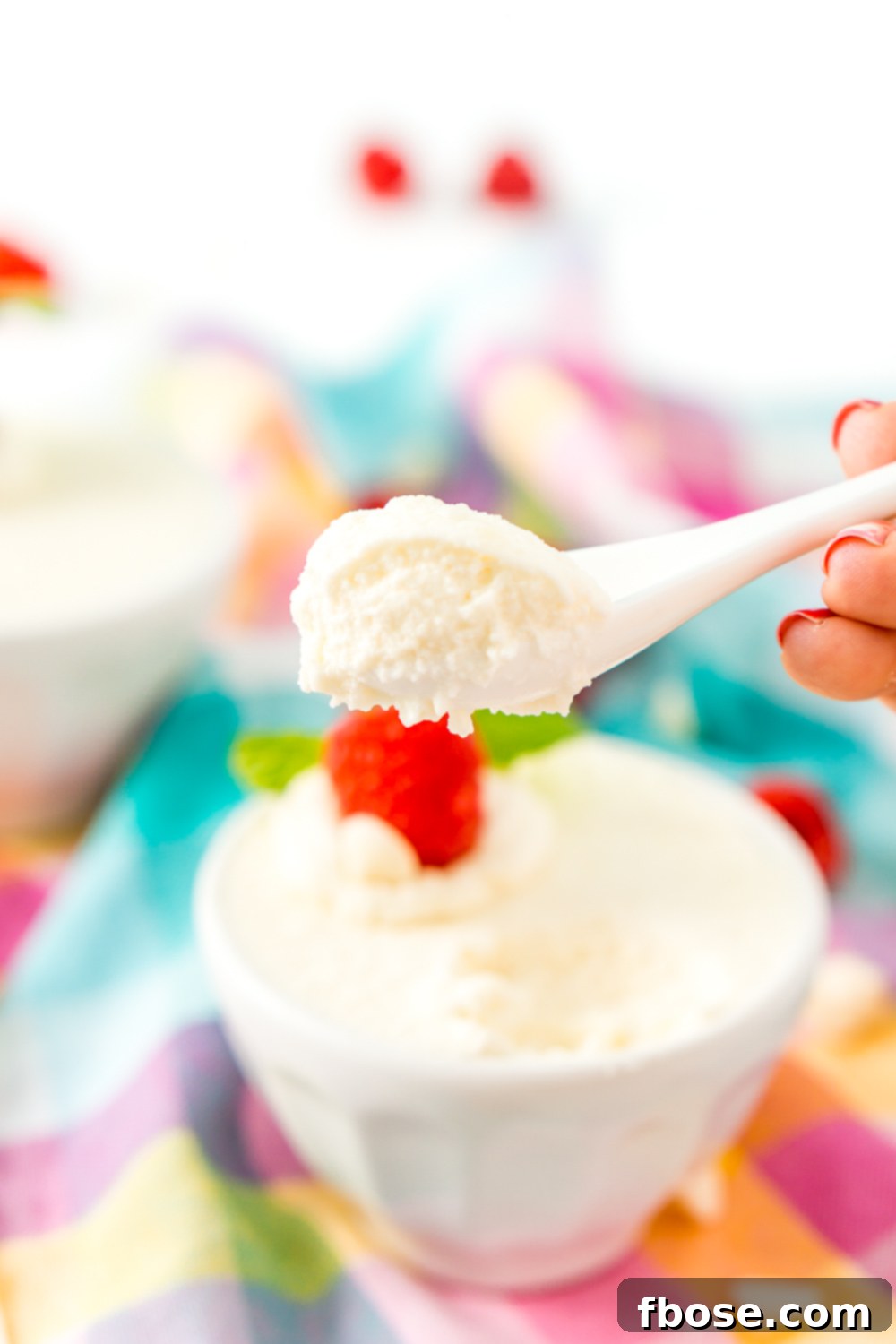 White chocolate mousse piped into a dessert cup and topped with fresh red berries and chocolate shavings.