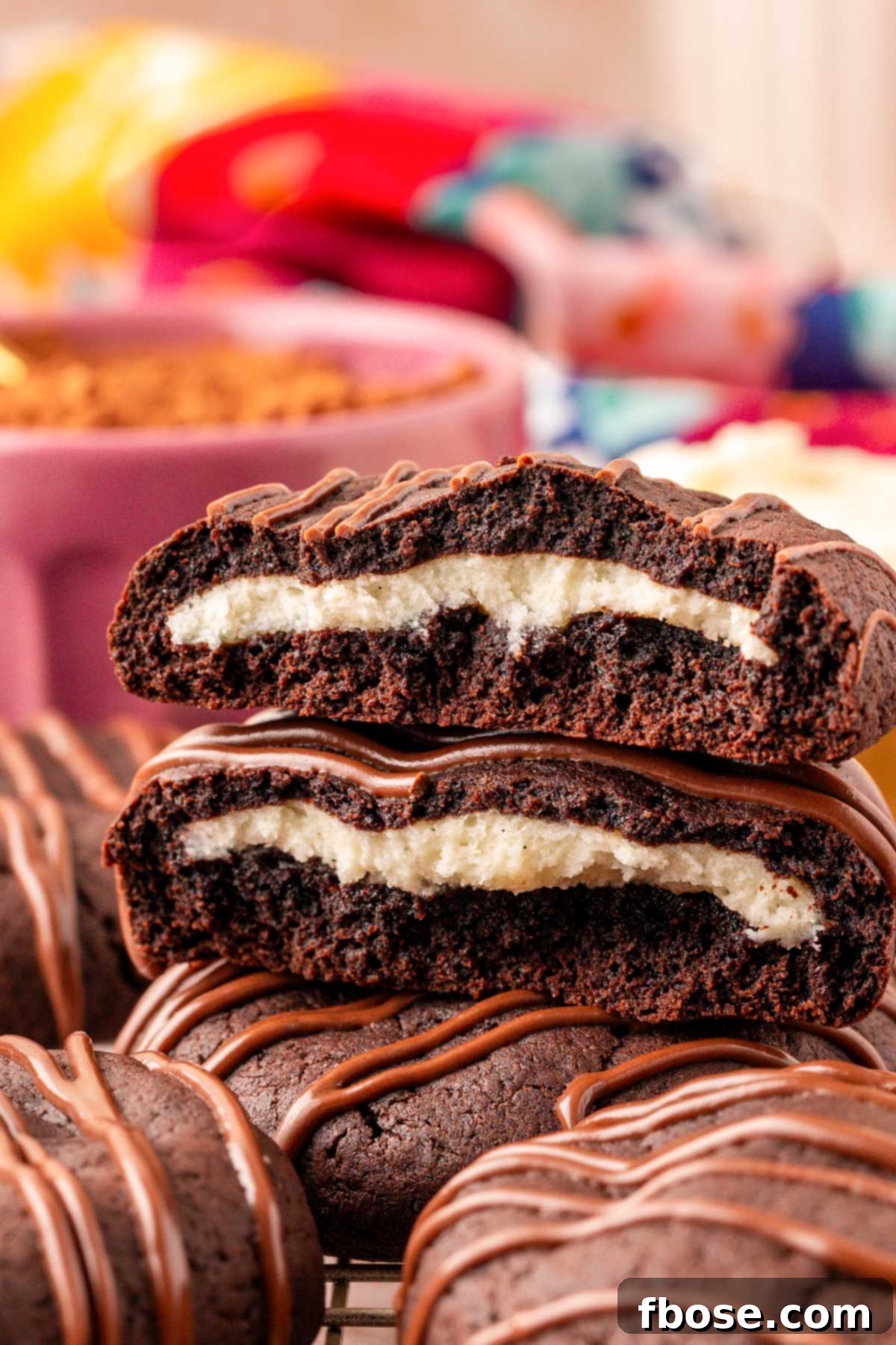Close up of chocolate cookies stuffed with cream cheese. The top cookie has been broken in half and stacked to show the inside.
