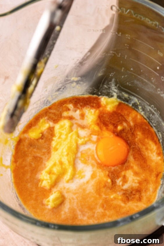 Egg and vanilla being added to other wet ingredients to make cookie dough.
