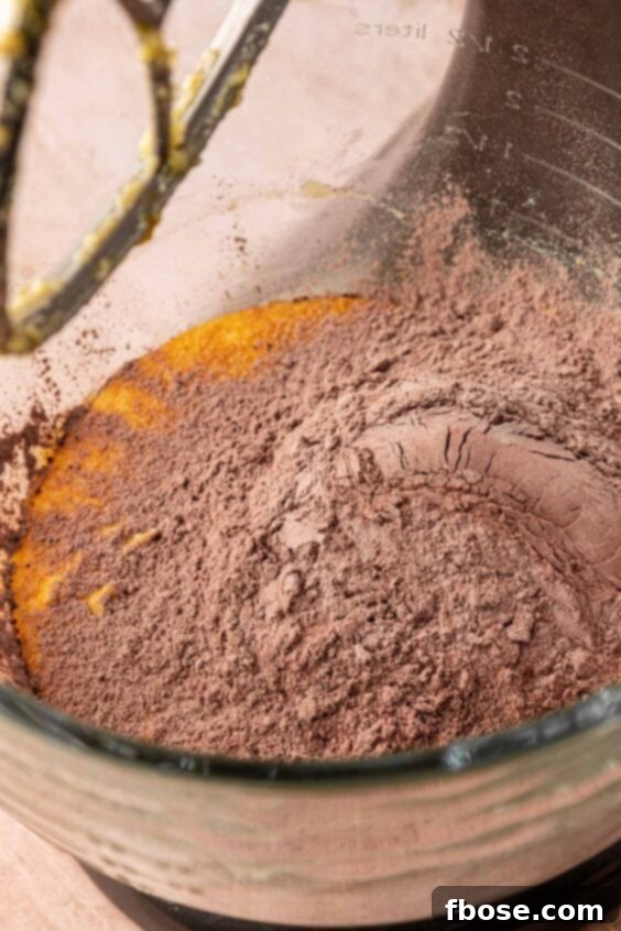 Dry ingredients being added to wet ingredients in a mixing bowl to make cookie dough.
