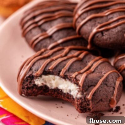 Close up of a chocolate cookie with cream cheese filling on a pink plate with a bite missing.